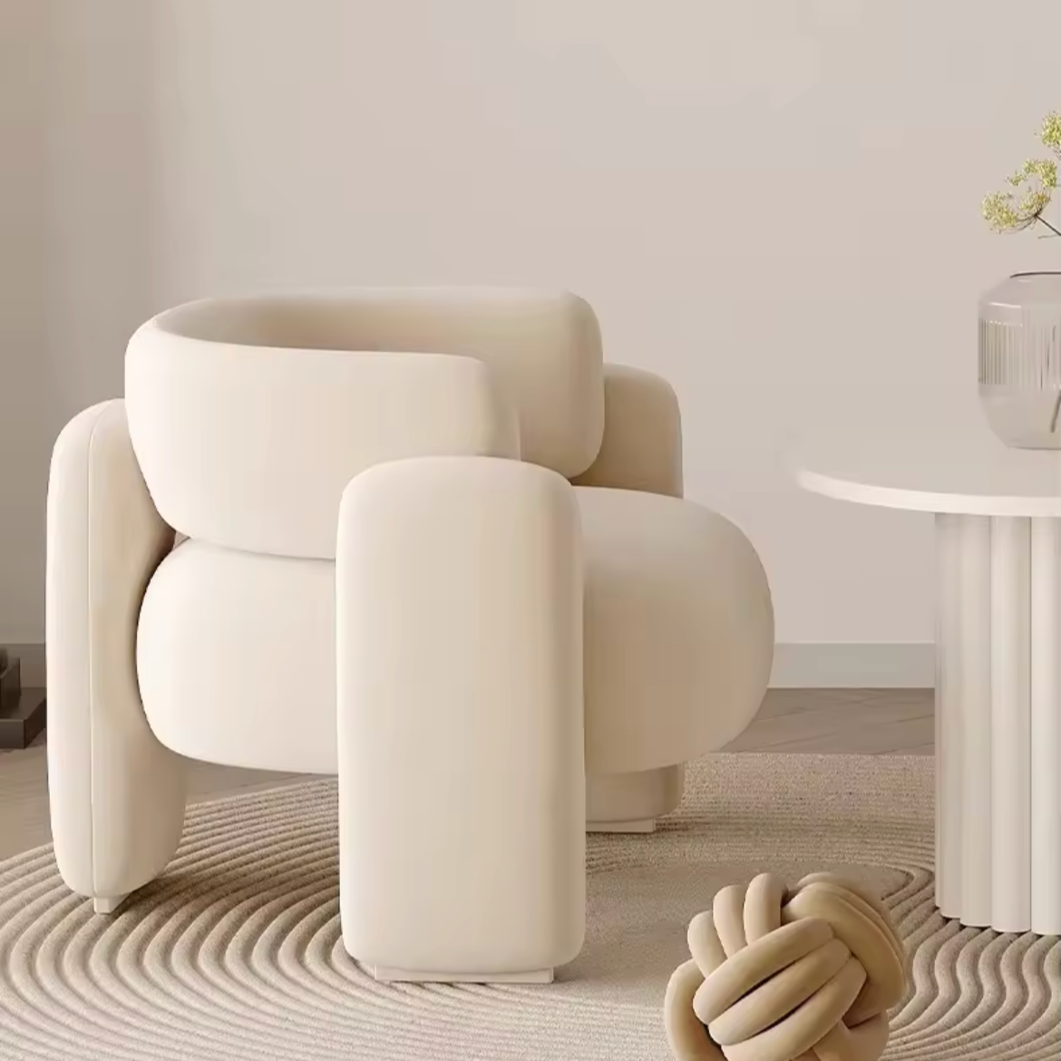 Modern beige armchair in a minimalistic room with a light gray wall and wooden floor.