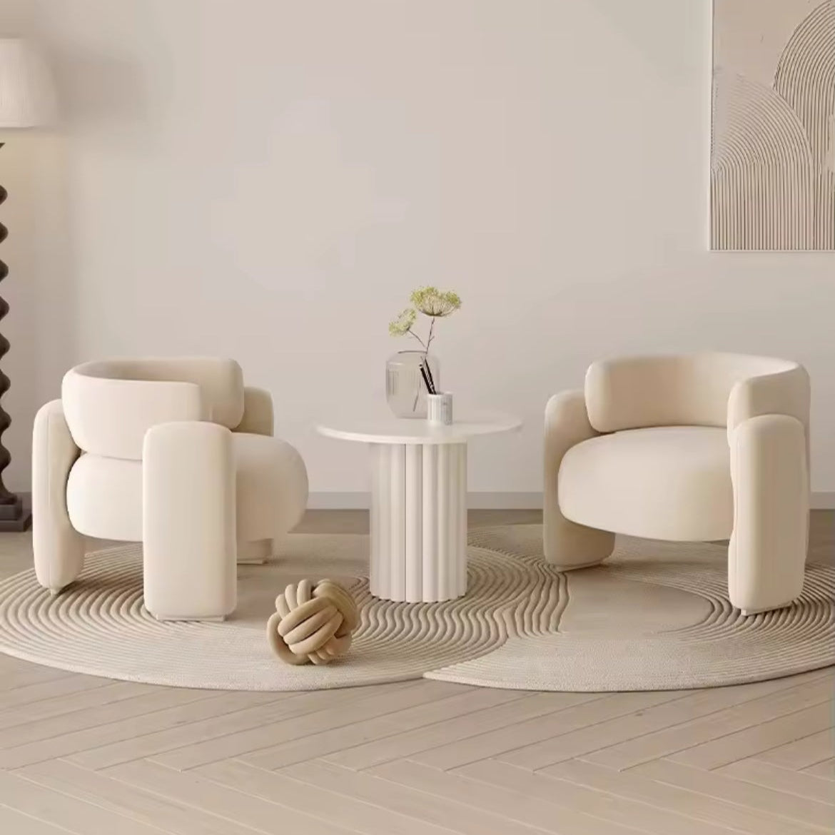 Modern interior with two cream-colored chairs and a small round table in a minimalistic room.