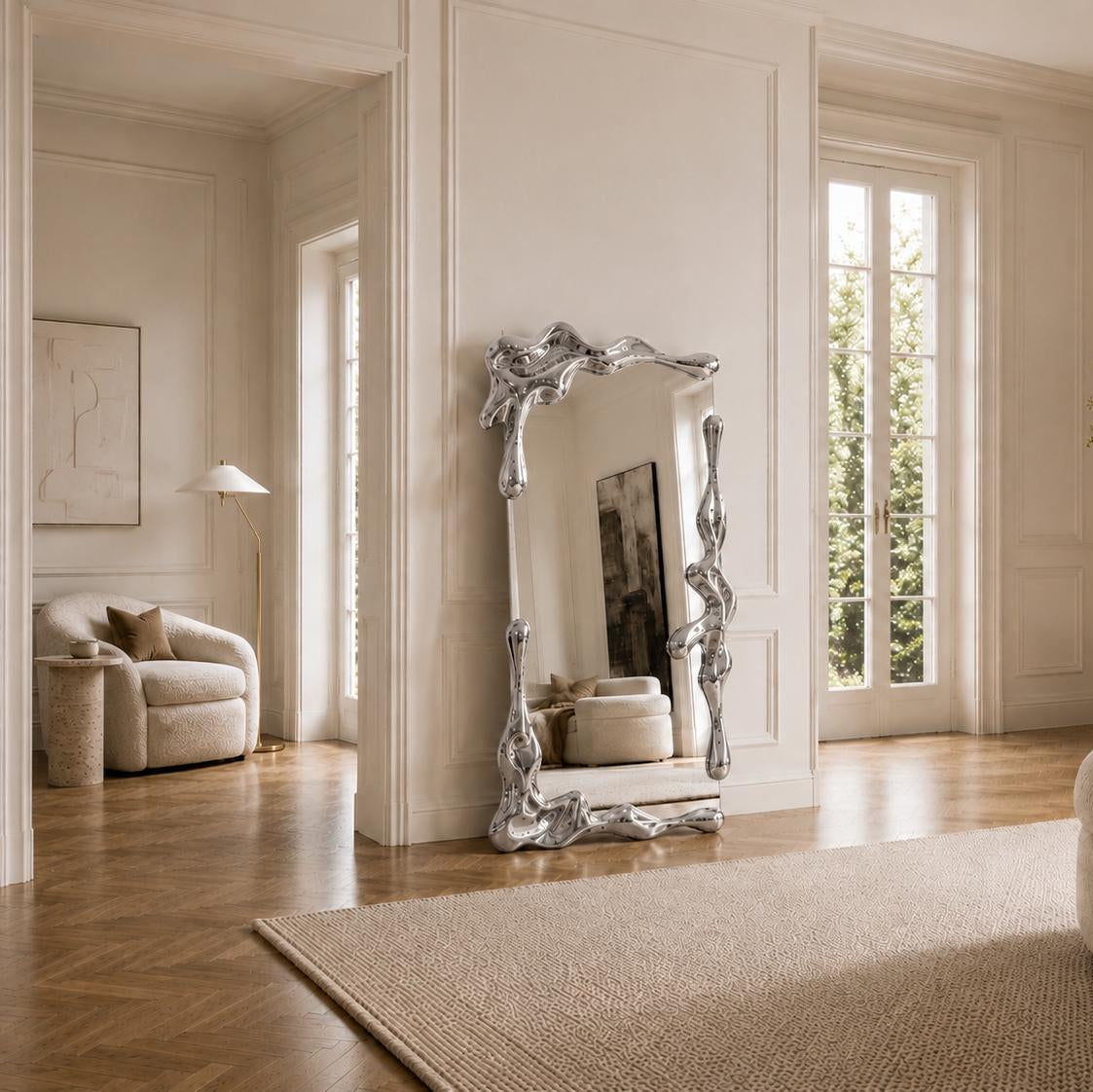 Sculptural full length liquid mirror with an organically shaped polished silver frame in a luxury contemporary interior.