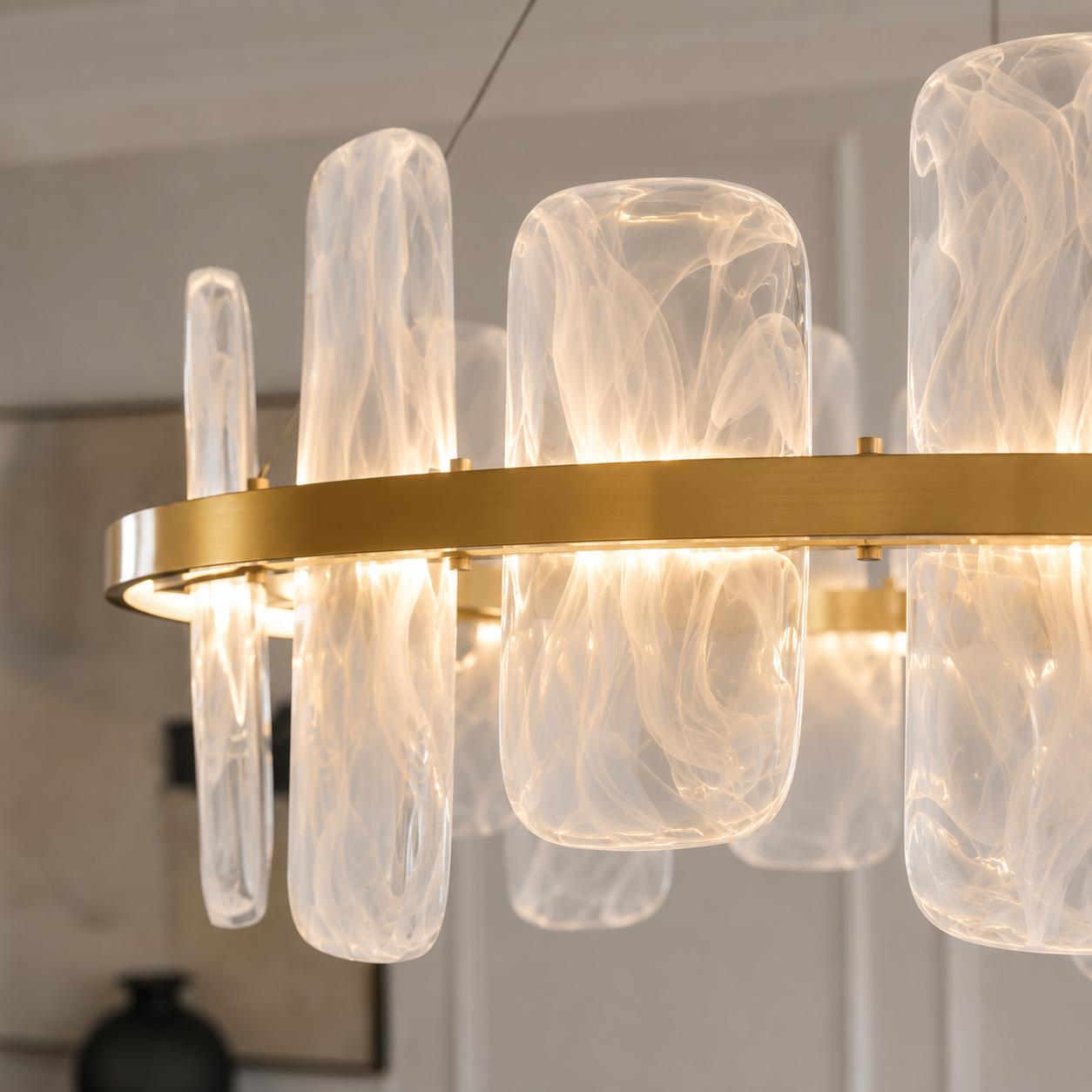 Contemporary brushed gold circular chandelier with smoked pattern glass shades suspended above a luxury dining space.