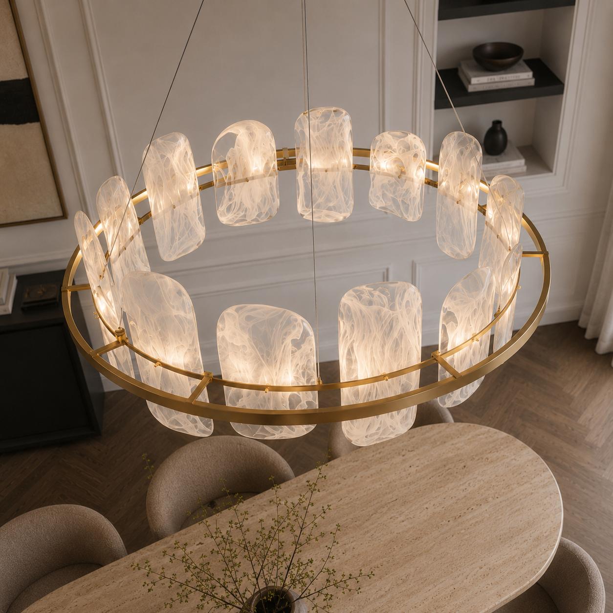 Contemporary brushed gold circular chandelier with smoked pattern glass shades suspended above a luxury dining space.