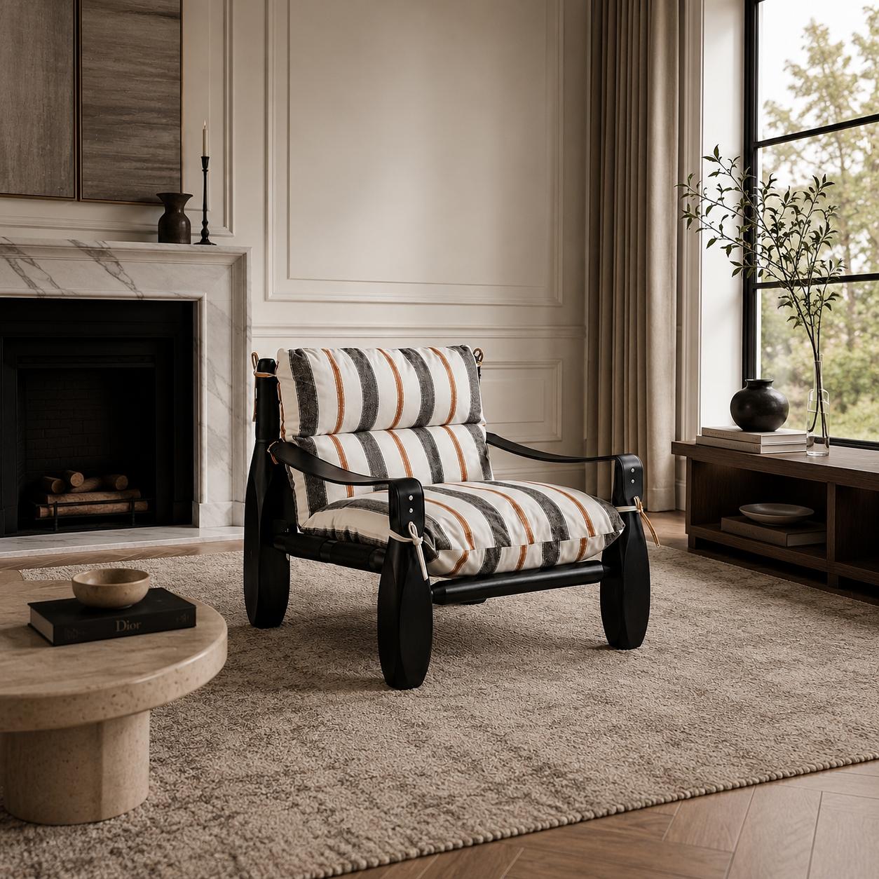 Designer armchair with striped upholstered cushions, a black finished wood frame and leather strap detailing in a luxury living room.