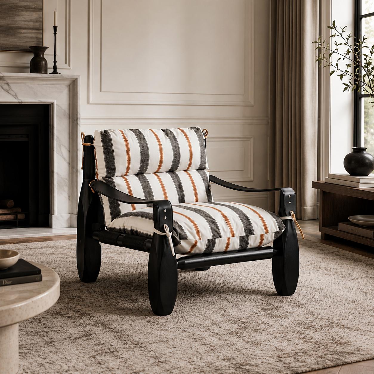 Designer armchair with striped upholstered cushions, a black finished wood frame and leather strap detailing in a luxury living room.