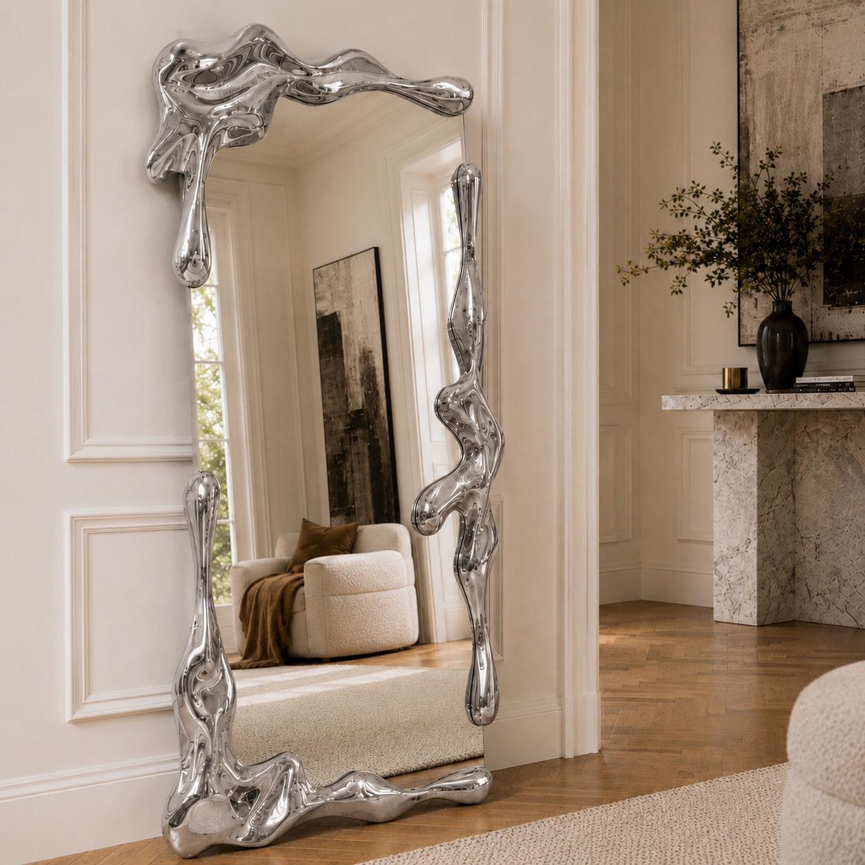Sculptural full length liquid mirror with an organically shaped polished silver frame in a luxury contemporary interior.