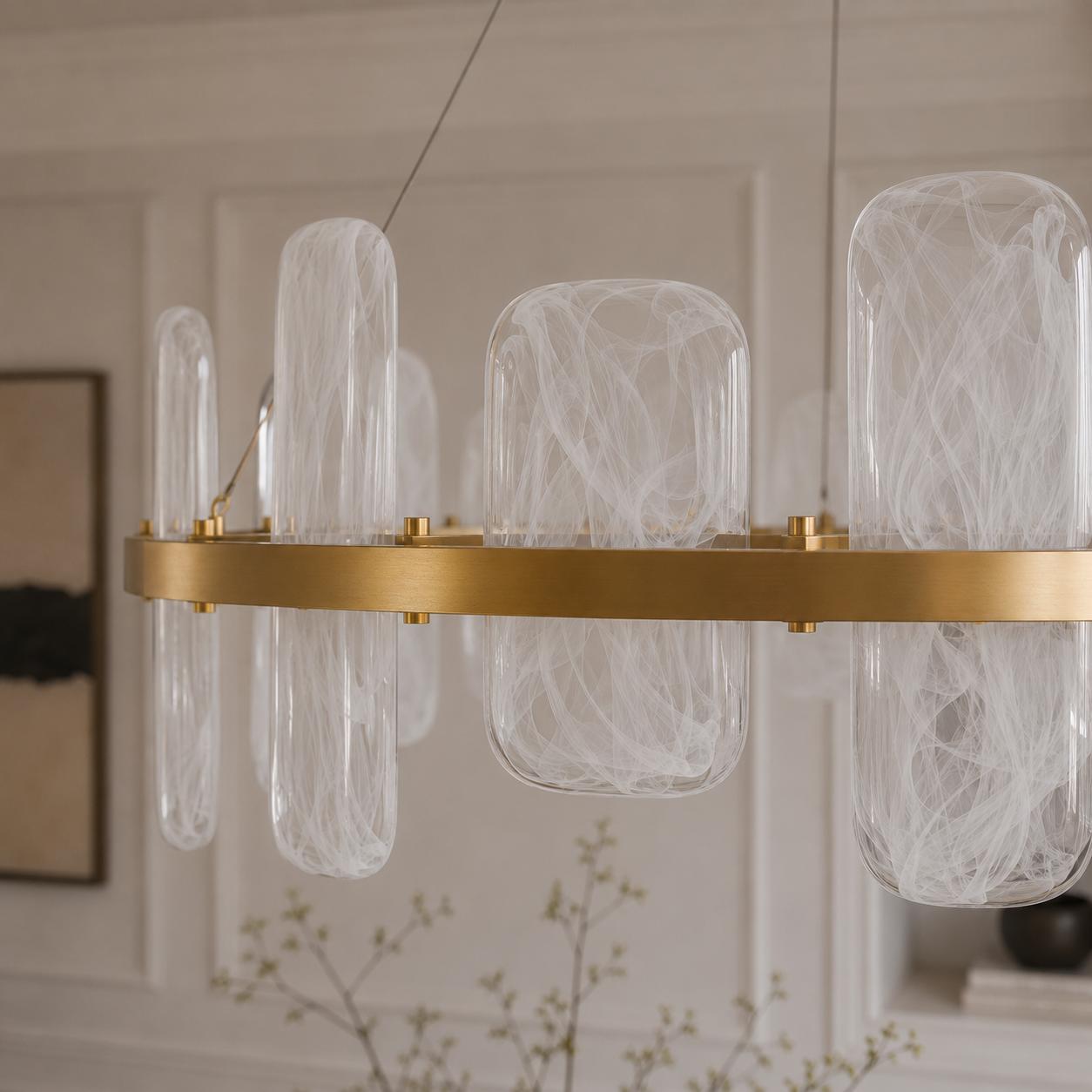 Contemporary brushed gold circular chandelier with smoked pattern glass shades suspended above a luxury dining space.